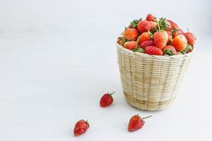 fresas frescas en una cesta sobre un fondo blanco foto