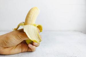 Open banana in hand  on white wooden table photo