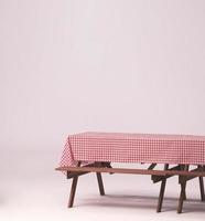 Picnic table and red checkered tablecloth with food and drink for outdoor party. Isolated photo