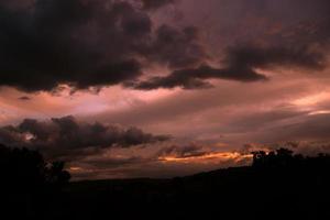 puesta de sol púrpura con nubes grises en primer plano. foto