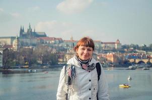 Close-up portrait of young girl tourist looking at camera and smile, Vltava river, Prague Castle photo