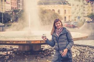 joven turista con chaqueta gris sonríe y sostiene agua mineral terapéutica foto