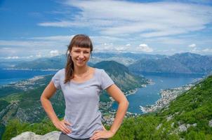 Young beautiful girl traveler with grey t-shirt posing and smile on top of mountain photo