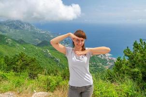 Young beautiful girl traveler with grey t-shirt posing and smile on top of mountain photo