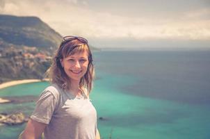 Close-up portrait of young caucasian girl traveler with grey t-shirt and sunglasses looking at camera photo