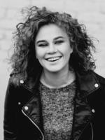 monochrome portrait of young beautiful cheerful woman with curly hair on white bricks wall background. Film stylization photo