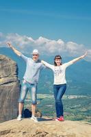 Young pare man and woman travelers stay, cuddle, smile and look at camera on Meteora stone rocks photo