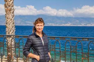 Young beautiful woman traveler looking at camera, smile, posing and keep hands in pockets photo