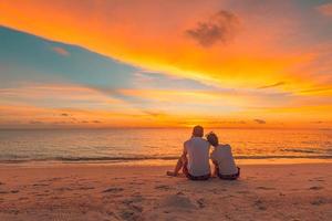 Romantic couple hugging on the beach on sunrise sunset. Honeymoon couple enjoying evening light relaxing on tropical summer vacation travel holiday. Two adults silhouettes lifestyle. photo