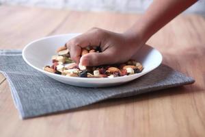 men reaching for many mixed nuts on table photo