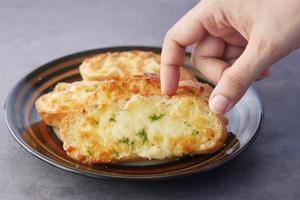 recoger a mano un pan de ajo en un plato foto