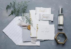 Wedding details flat lay. Wedding invitation and scroll paper. Bottle with fragrance. Ring box. Simple bouquet. photo