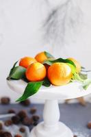 mandarinas naranjas sobre fondo gris en la decoración de año nuevo con piñas marrones y hojas verdes. decoración navideña con mandarinas. deliciosa dulce clementina. foto