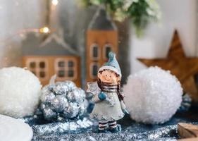 Porcelain figurines of children in a Christmas decor. Winter figurines of a boy and a girl with gifts on the background of houses and cones. Christmas Greeting Card. Copy space. photo