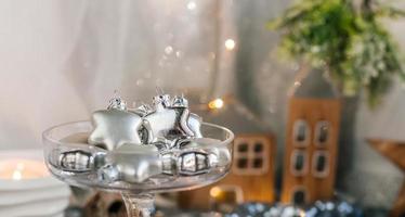 estrellas de plata de cristal en un jarrón de cristal. juguetes de árbol de navidad en un vaso sobre un fondo de tela brillante y conos de abeto. copie el espacio foto