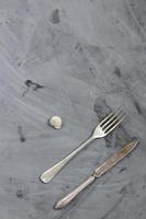 caracol, tenedor y cuchillo sobre fondo de hormigón gris. copie el espacio