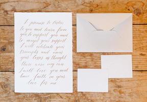 Wedding details flat lay on wooden background. Wedding invitation. Wedding bouquet. Mock up. Envelope. Copy space. photo