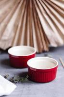 Small glazed ceramic ramekin. Red baking cup for cupcakes, muffins on a gray and white background. Ceramic baking dish. photo