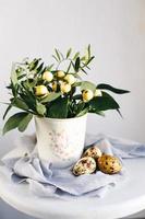 Easter eggs with green branches and yellow berries on white and gray background. Easter holiday, front view photo