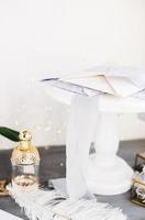 Bottle of perfume. Spring bouquet on gray concrete table. Roses, tulips and lisianthus. White feather. photo