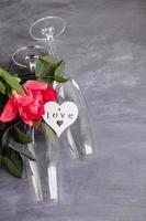 Composition with glass for champagne. Flowers and hearts on grey concrete background. photo