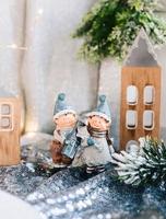 Porcelain figurines of children in a Christmas decor. Winter figurines of a boy and a girl with gifts on the background of houses and cones. Christmas Greeting Card. Copy space. photo