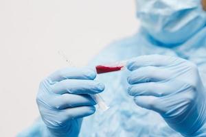 Close up of doctor hand holding blood sample. Medical equipment. Blood test. A doctor wearing personal protective equipment including mask, goggle, and suit to protect COVID-19 coronavirus infection. photo