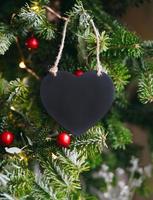 corazón de madera negra sobre un fondo de ramas de abeto. composición de navidad año nuevo. maqueta, copie el espacio para el día de san valentín. foto