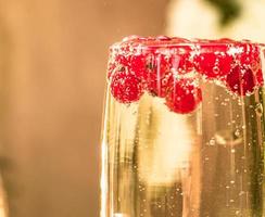 Sparkle wine in glass with red currant berries photo