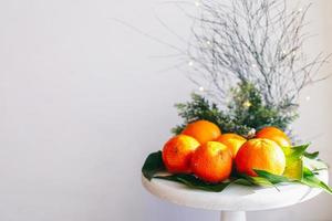 Orange tangerines on grey background in New Year's decor with brown pine cones and green leaves. Christmas decoration with mandarins. Delicious sweet clementine. photo