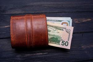 Dollars in a brown wallet on a black cement background. Financial and business concept. photo