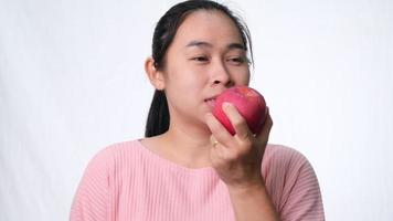 Aziatische vrouw met een appel met een hapje en een glimlach met sterke tanden