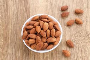 Almonds in bowl on wooden table.  Close up. Selected focus photo