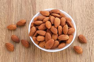 Almonds in bowl on wooden table.  Close up. Selected focus photo