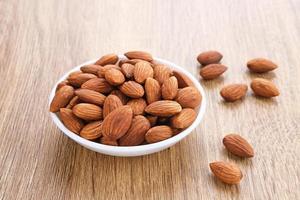 Almonds in bowl on wooden table.  Close up. Selected focus photo