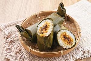 Arem-arem, a traditional Indonesian food made from rice filled with vegetables, chicken, meat or tempeh wrapped in banana leaves. Arem-arem is popular as a breakfast substitute. Selected focus. photo
