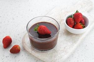 pudín de chocolate con fresas en vaso sobre mesa blanca. foco seleccionado. foto