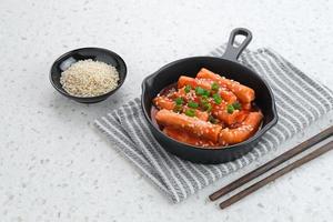 tteokbokki o topokki, palo de pastel de arroz salteado, popular comida callejera coreana con salsa gochujang picante y semillas de sésamo. foto