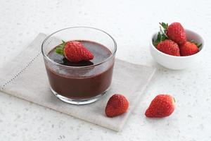 pudín de chocolate con fresas en vaso sobre mesa blanca. foco seleccionado. foto