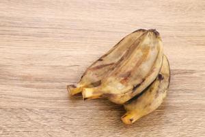 pisang kukus o plátano al vapor, comida tradicional indonesia, un refrigerio saludable. servido en mesa de madera. de cerca. foto