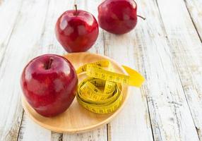 Red apple and yellow tape measure on a wooden table photo