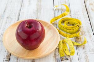 Red apple and yellow tape measure on a wooden table photo