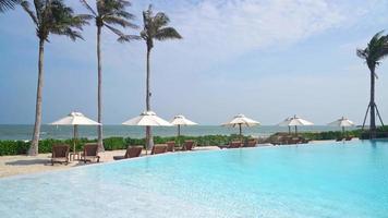 parasol avec lit piscine autour de la piscine avec fond de mer océan - concept de vacances et de vacances