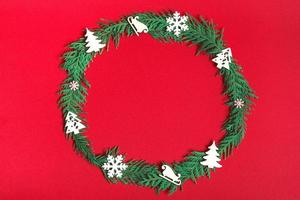 Christmas wreath of fir branches and decorations on a red background. Flat lay, top view, copy space. festive composition photo