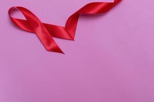 Top view on pink background with red ribbon concept December 1st International AIDS Day close-up. photo