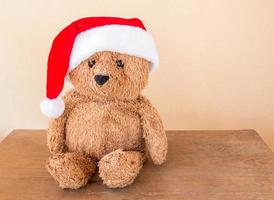 Teddy bear wearing a christmas hat on wooden table photo