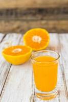 Glass of freshly pressed orange juice on wooden table photo
