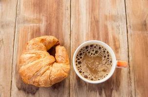 Croissant and coffee for breakfast on old wooden table photo