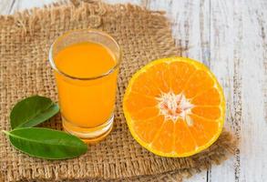 Glass of freshly pressed orange juice with sliced orange on wooden table photo