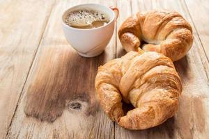Croissant and coffee for breakfast on wooden table photo